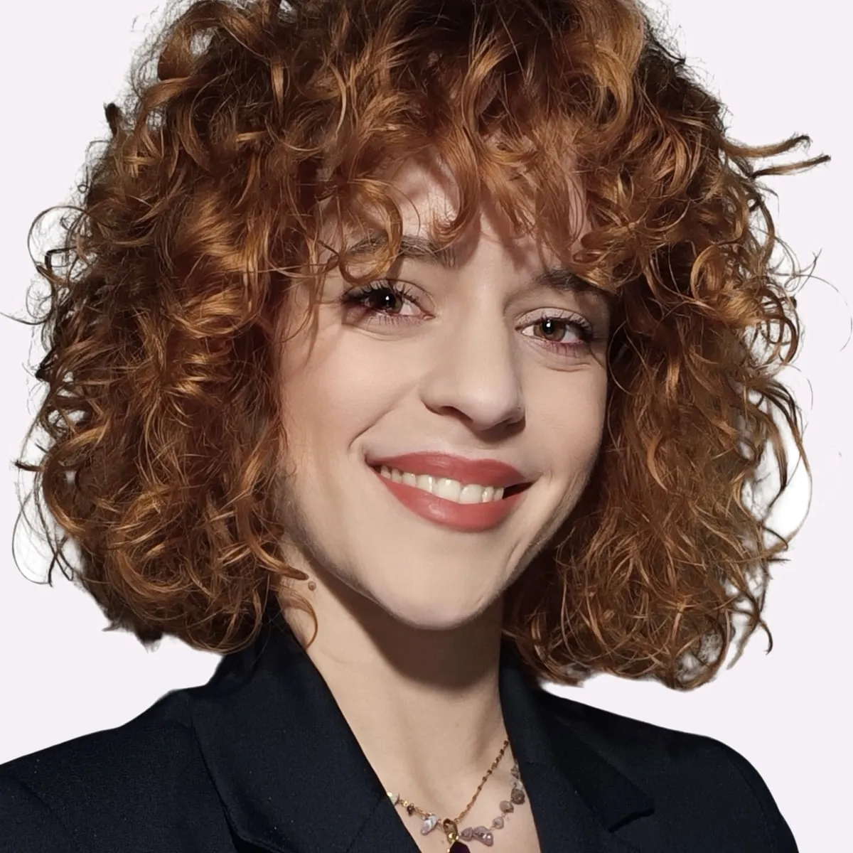 Katerina Tasidou, smiling, with curly auburn hair and a black blazer
